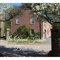 Die Fruehstueckspension Le Grand Jardin in Neufchateau in den Ardennen bietet einen charmanten Aussenbereich mit bluehenden Baeumen und einer einladenden Atmosphaere.