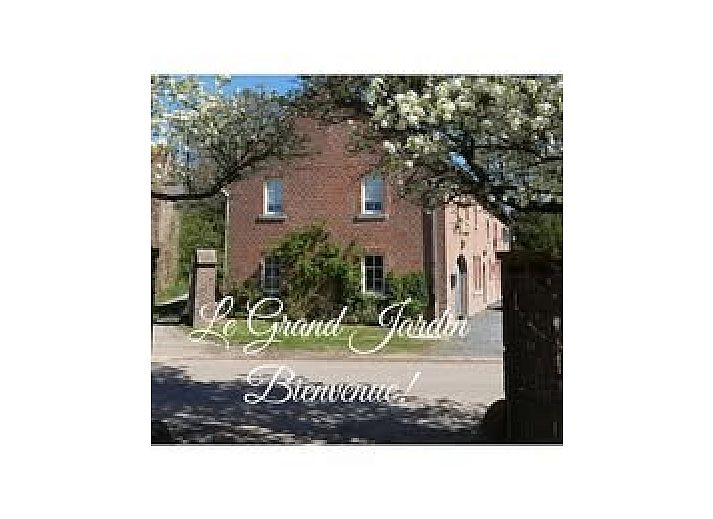 Die Fruehstueckspension Le Grand Jardin in Neufchateau in den Ardennen bietet einen charmanten Aussenbereich mit bluehenden Baeumen und einer einladenden Atmosphaere.