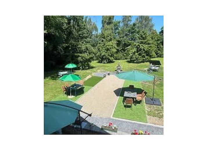 Die Fruehstueckspension Le Grand Jardin in Neufchateau in den Ardennen bietet einen charmanten Aussenbereich mit bluehenden Baeumen und einer einladenden Atmosphaere.