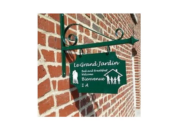 Die Fruehstueckspension Le Grand Jardin in Neufchateau in den Ardennen bietet einen charmanten Aussenbereich mit bluehenden Baeumen und einer einladenden Atmosphaere.