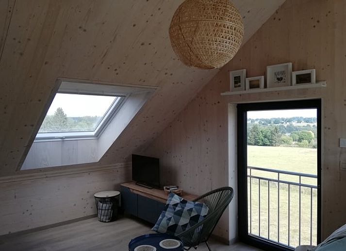 Buitenaanzicht van Huisje in Tailles, bed and breakfast in de Ardennen, met zonnige tuin en blauwe lucht.