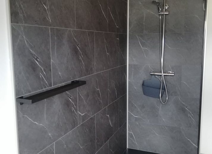 Buitenaanzicht van Huisje in Tailles, bed and breakfast in de Ardennen, met zonnige tuin en blauwe lucht.