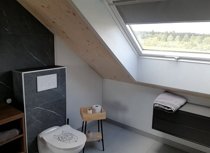 Buitenaanzicht van Huisje in Tailles, bed and breakfast in de Ardennen, met zonnige tuin en blauwe lucht.