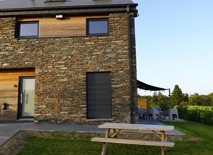 Exterieur van Vakantiehuisje in Tailles, Ardennen. Moderne architectuur met stenen en houten elementen en een zonnig terras.