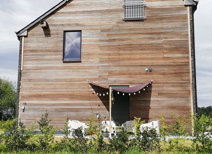 Exterieur van Vakantiehuisje in Tailles, Ardennen. Moderne architectuur met stenen en houten elementen en een zonnig terras.