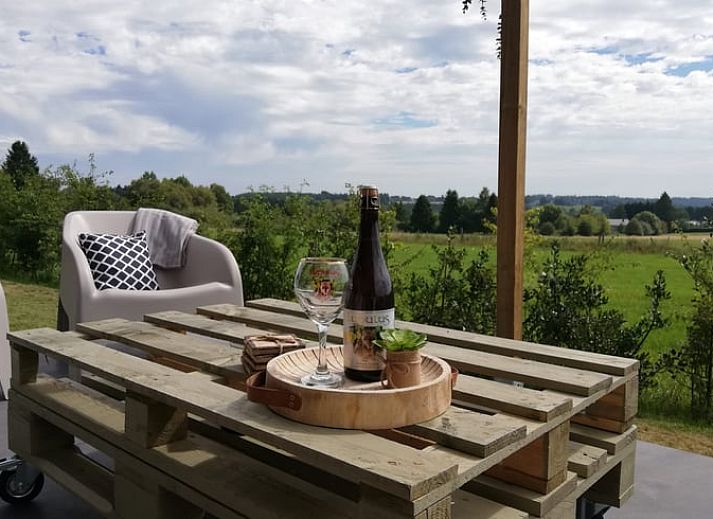 Vakantiehuisje in Tailles, Ardennen bij zonsondergang. Rustieke charme met picknicktafel en uitzicht op de omliggende natuur.
