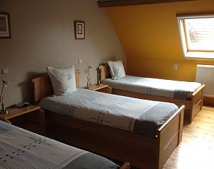 Lichte slaapkamer met drie bedden in Varlet Farm bed and breakfast, Poelkapelle, met geel accent.